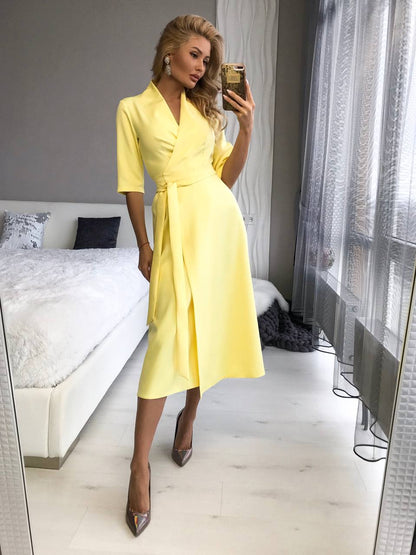 Woman in a yellow dress taking a mirror selfie in a bedroom.