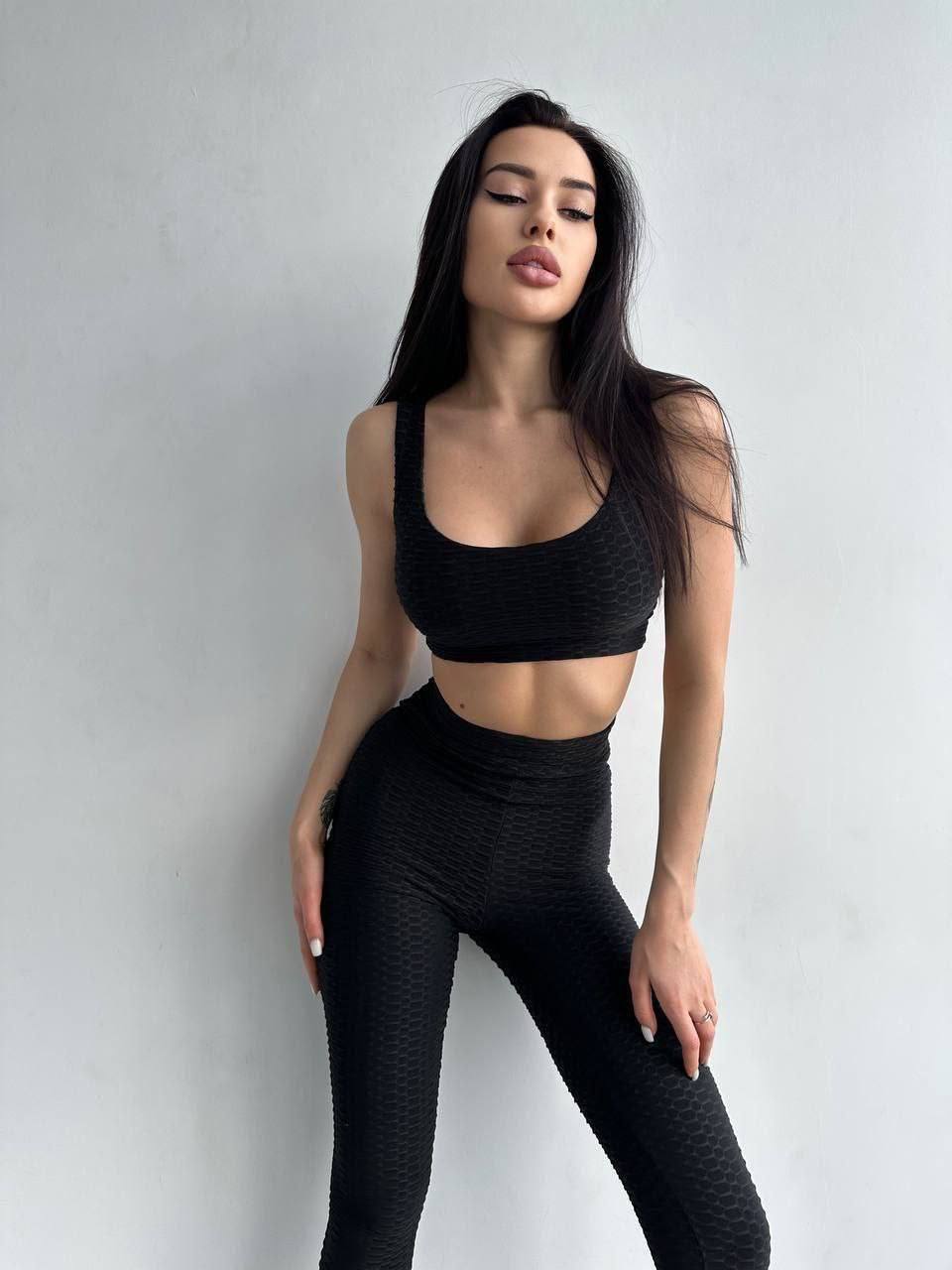 Woman wearing a black athletic outfit against a plain background