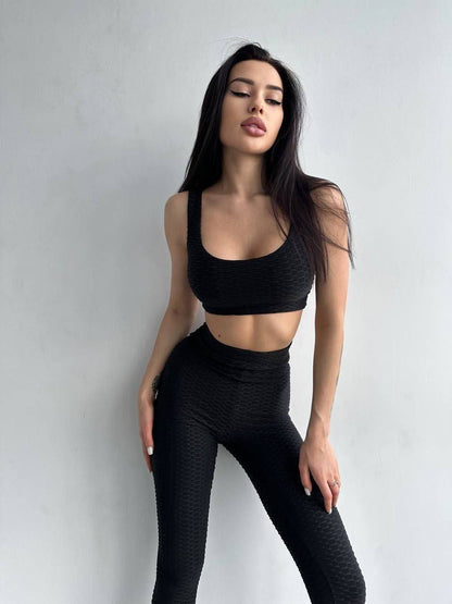 Woman wearing a black athletic outfit against a plain background