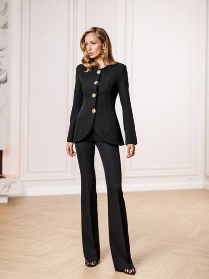 Woman wearing a black suit with gold buttons in an elegant room.