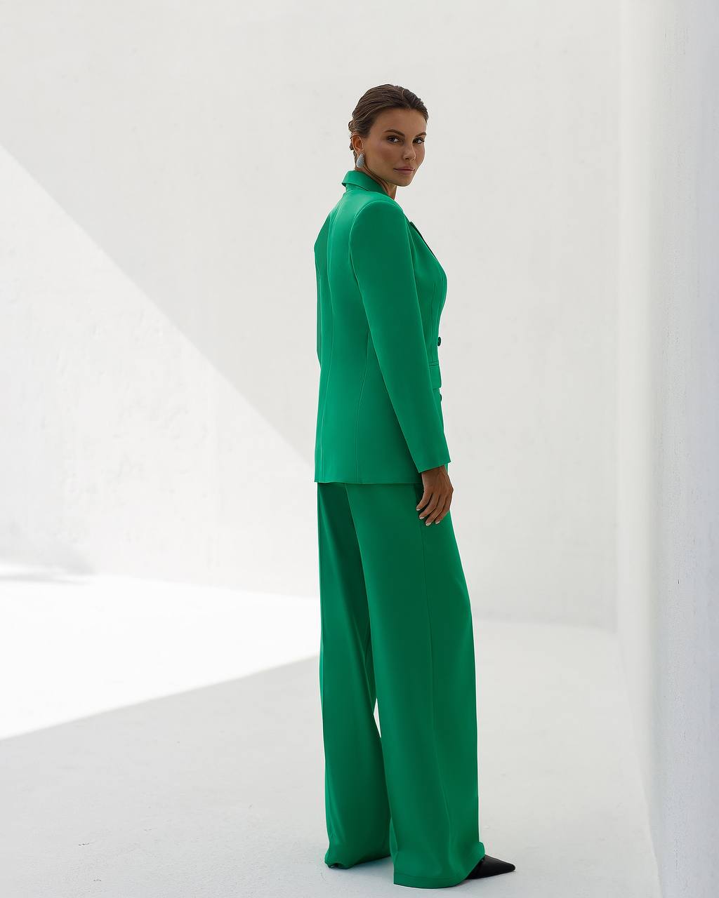 Woman wearing a green suit standing against a white background