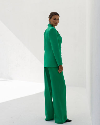 Woman wearing a green suit standing against a white background