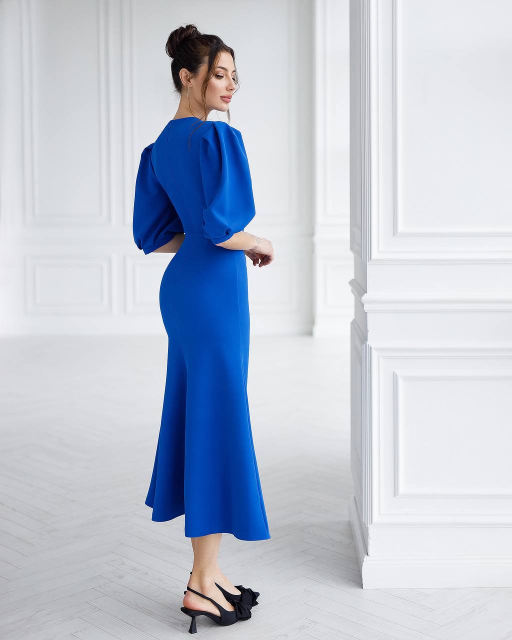 Woman in a blue dress standing in a white room