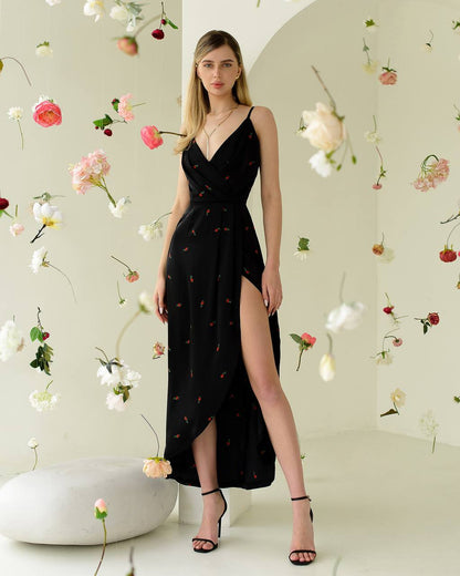 Woman in a black dress with floral patterns standing against a floral wallpapered wall.