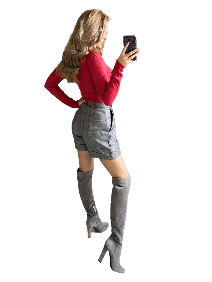 Woman wearing a red top and gray knee-high boots taking a selfie.