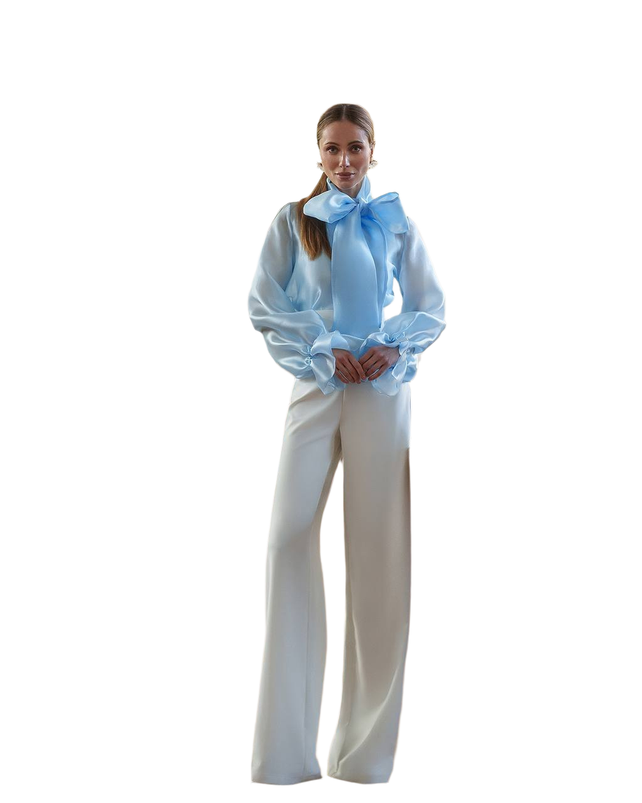 Woman wearing a white blouse with a blue bow and white pants on a white background