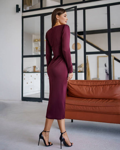 Woman in a burgundy dress standing in a modern room with a brown sofa and glass walls.