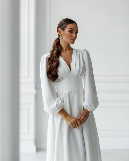 Woman wearing a white dress with long sleeves in a minimalistic setting