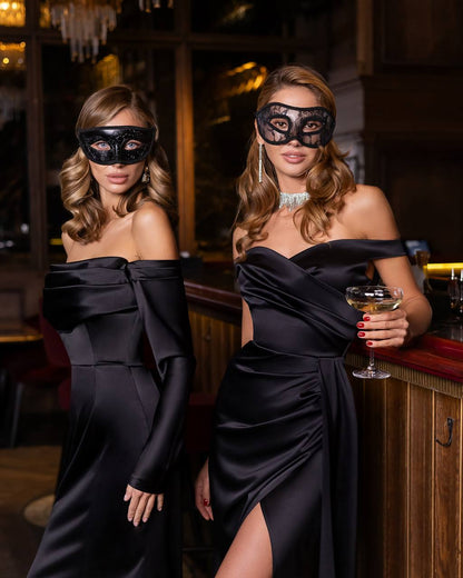 Two women in black dresses and masks in a dimly lit bar setting.