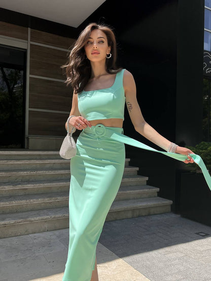 Woman in a mint green outfit standing on steps outdoors
