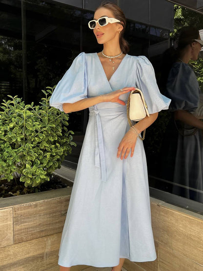 Woman in a light blue dress standing outdoors with a blurred background
