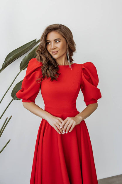Woman wearing a red dress with puff sleeves against a white background