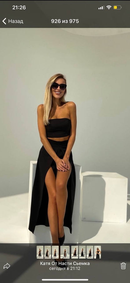 Woman in a black outfit posing against a plain background