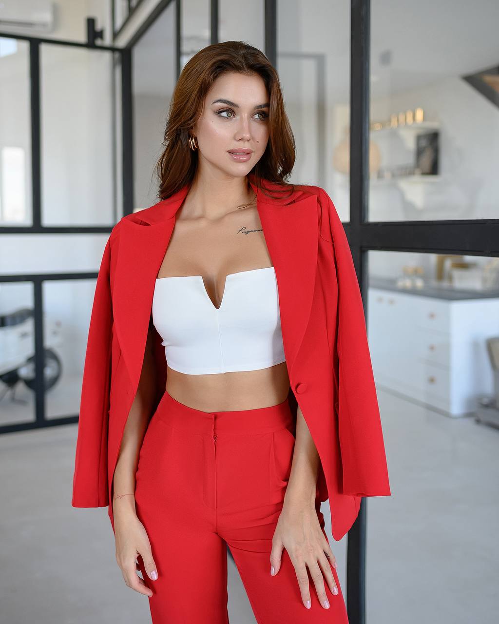 Woman wearing a red blazer and pants with a white top in an indoor setting