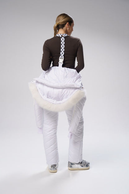 Person wearing a brown top with a checkered pattern, white puffy pants, and sneakers on a gray background