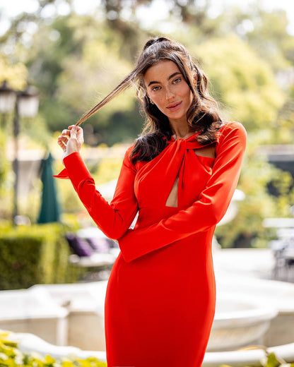 Woman in a red dress posing outdoors with trees in the background