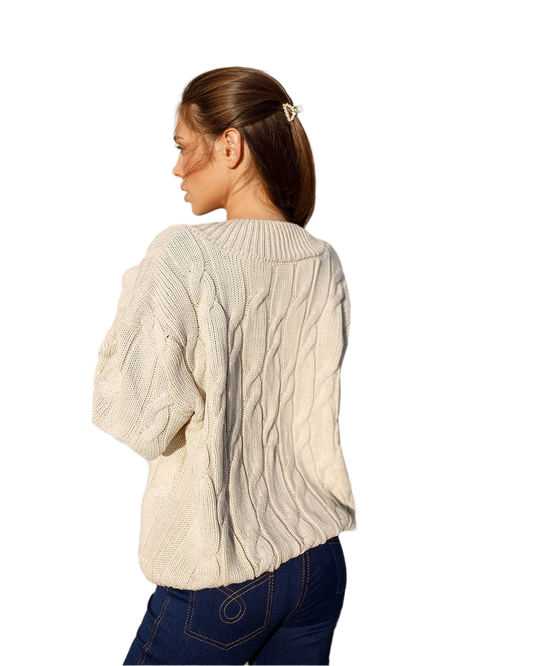 Woman wearing a cream cable knit sweater on a white background