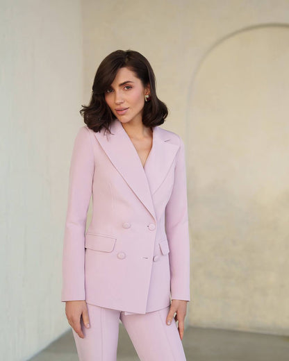 Woman wearing a light pink suit against a plain background