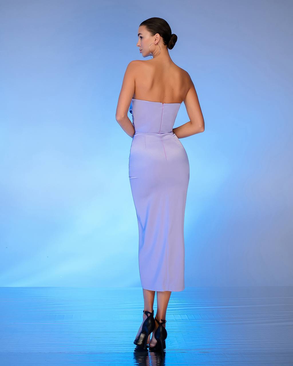 Woman wearing a strapless lavender dress on a blue gradient background
