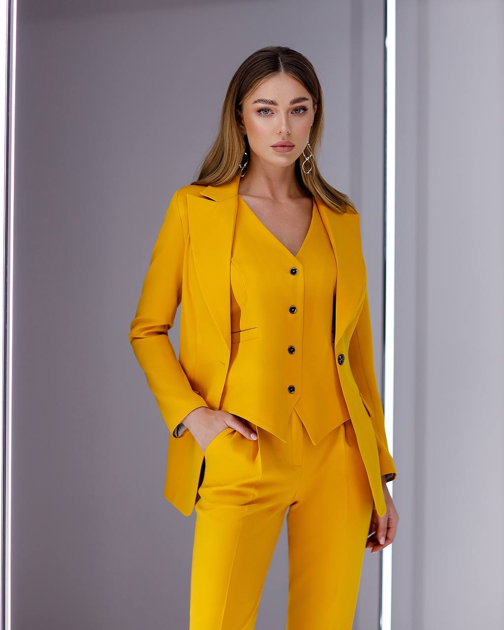 Woman wearing a yellow suit against a gray background