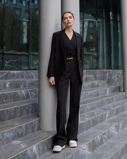 Woman in a black suit standing on steps outside a modern building