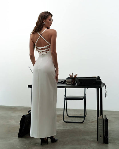 Woman in a white dress with thin straps standing in an office setting.