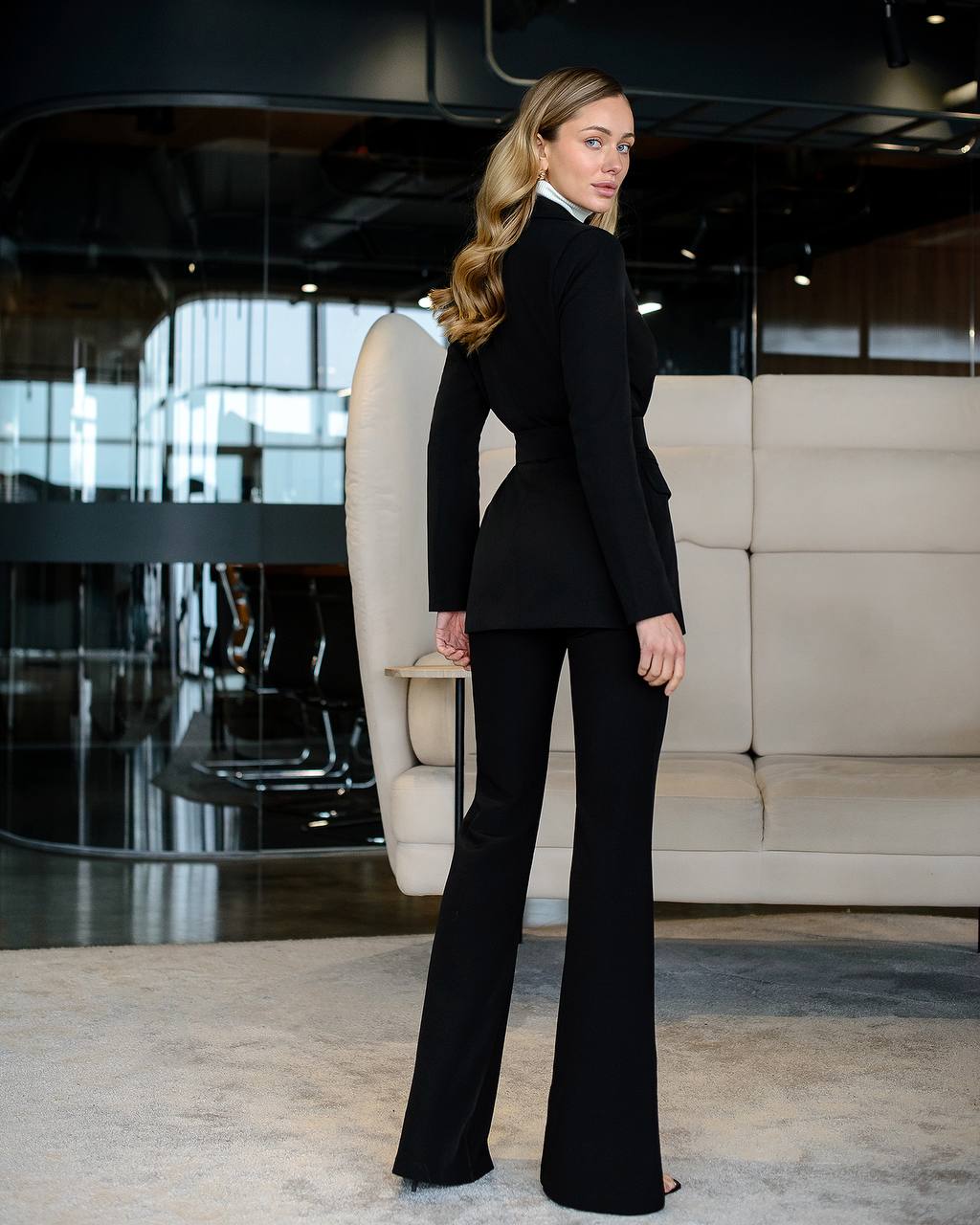 Woman in a black suit standing in an elegant interior setting
