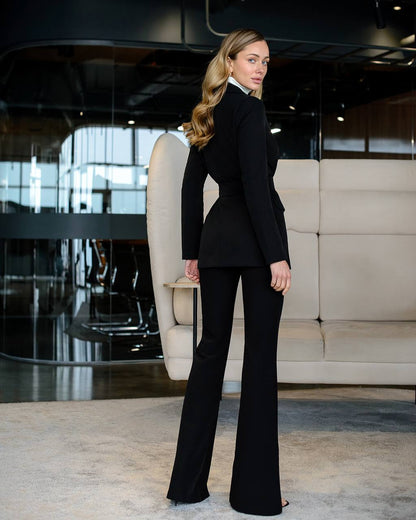 Woman in a black suit standing in an elegant interior setting