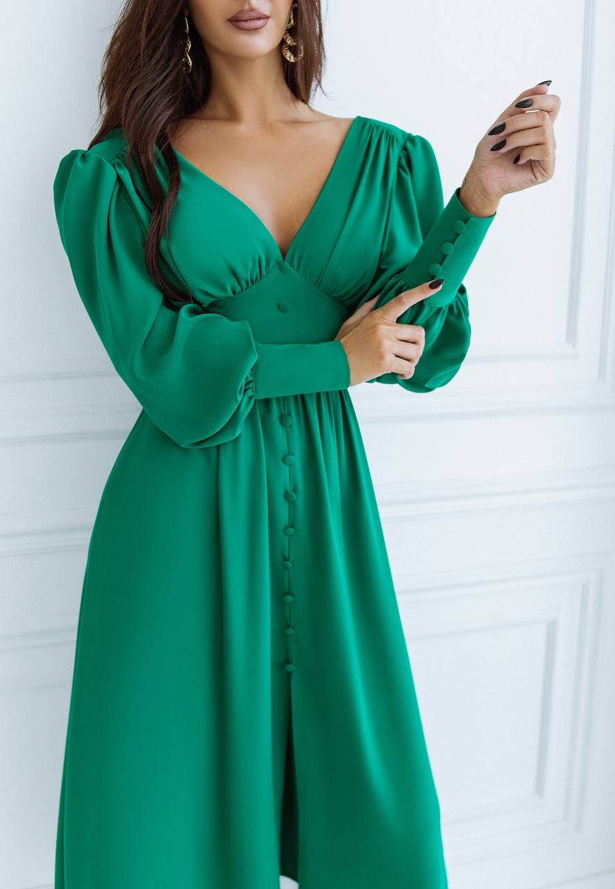 Green dress with long sleeves worn by a person against a white background