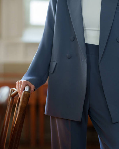 Person wearing a navy suit holding a suitcase indoors