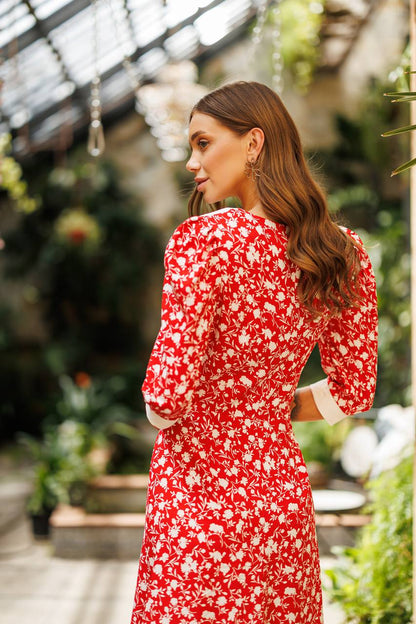 Woman in a red floral dress standing in a greenhouse