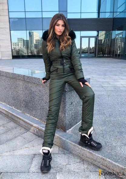 Woman in green winter outfit posing on steps with modern building in background