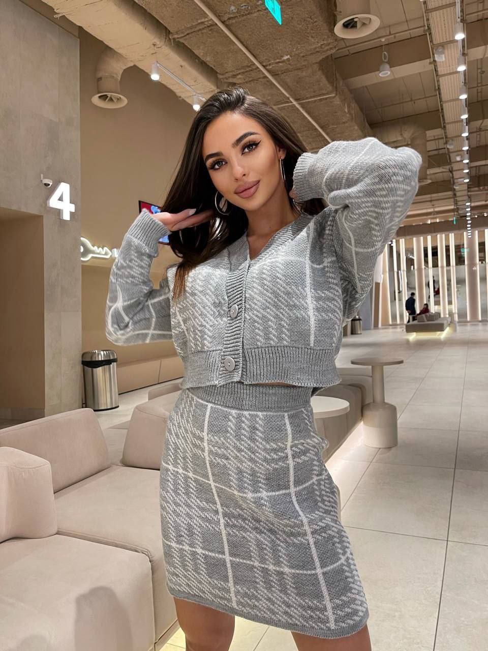 Woman in a gray checkered outfit posing in a modern indoor setting