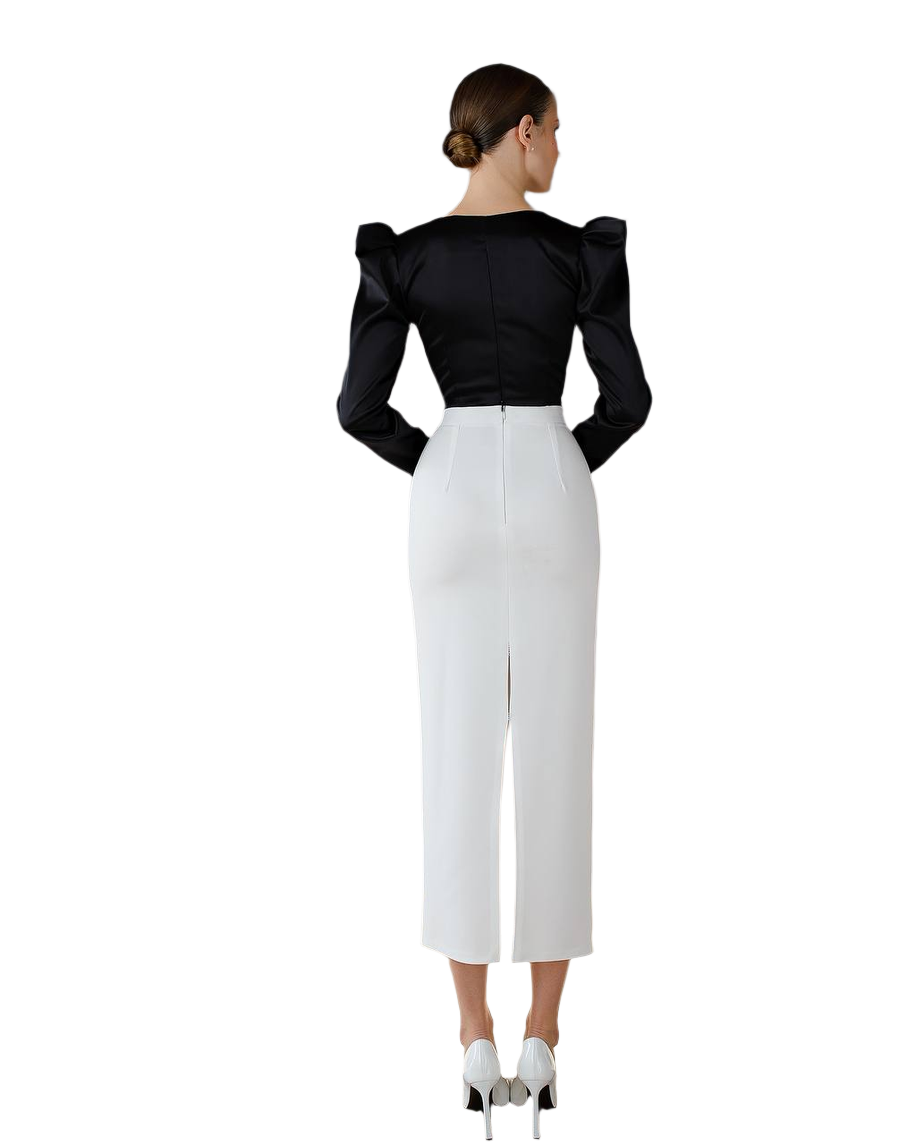 Woman wearing a black top with puffed sleeves and white pants on a white background