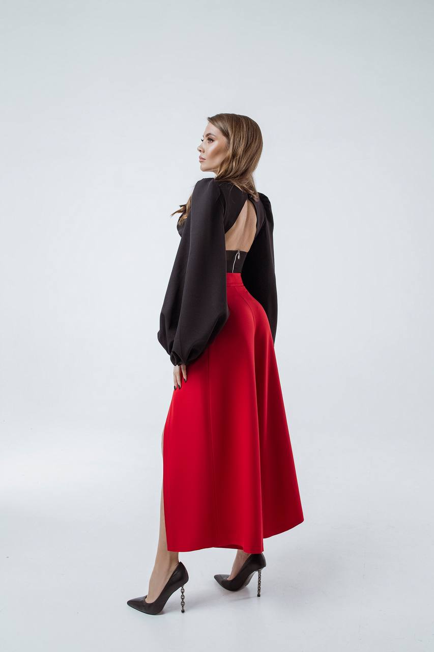 Woman wearing a black top with cut-out design and a red skirt on a white background