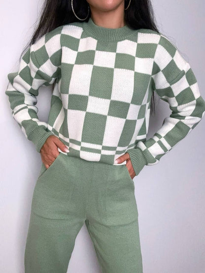 Person wearing a green and white checkered sweater with matching pants against a plain background