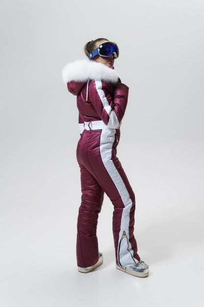Person wearing a maroon and white ski suit with goggles on a white background