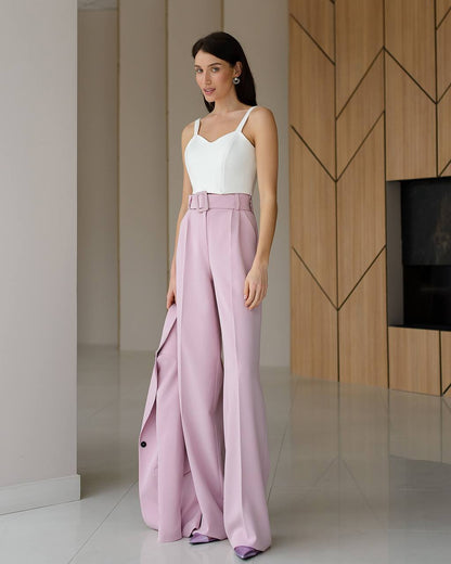 Woman wearing a white top and pink pants in a modern room.