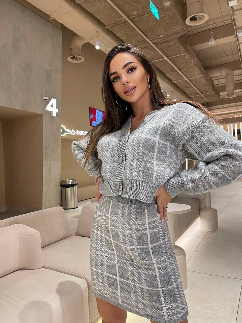 Woman in a gray checkered outfit standing in a modern indoor setting
