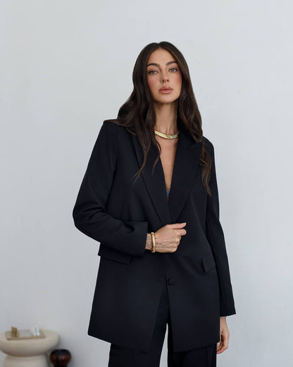 Woman wearing a black suit against a plain background