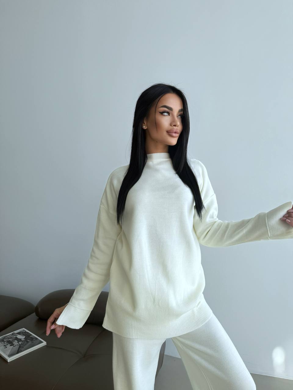 Woman wearing a white outfit standing in a minimalistic room.