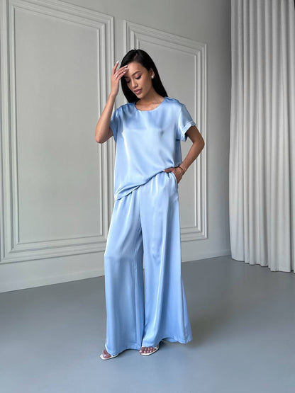 Woman wearing a light blue outfit in a minimalistic room.