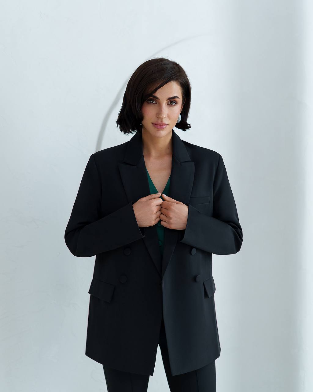 Woman wearing a black suit against a white background