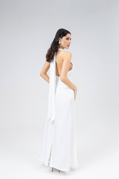 Woman wearing a white dress with a halter neck design on a plain background