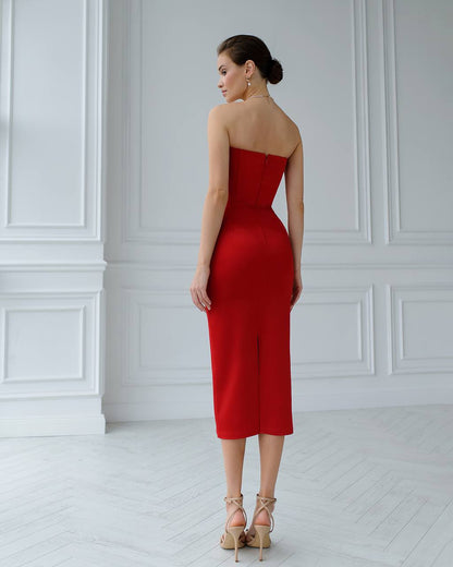 Woman wearing a red strapless dress in a white room