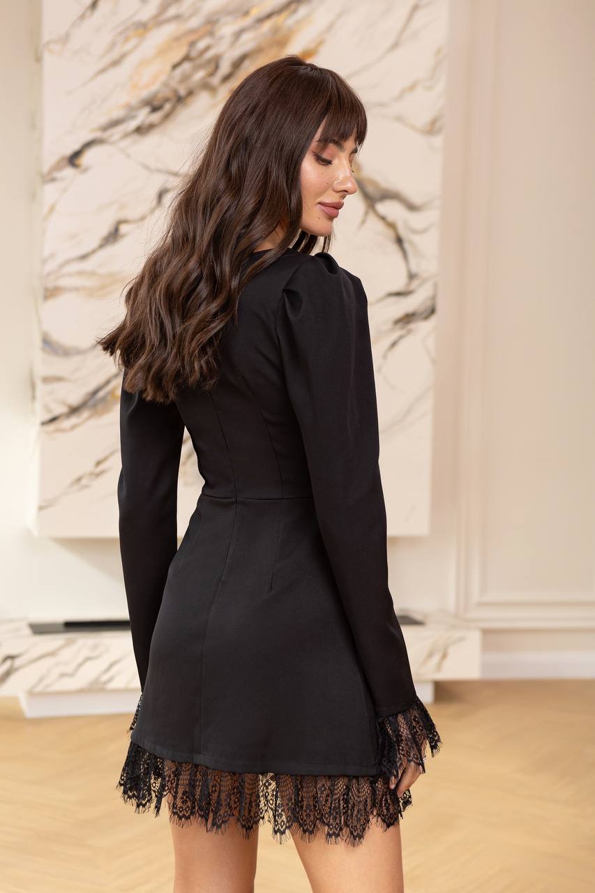Woman wearing a black dress with lace details in an indoor setting