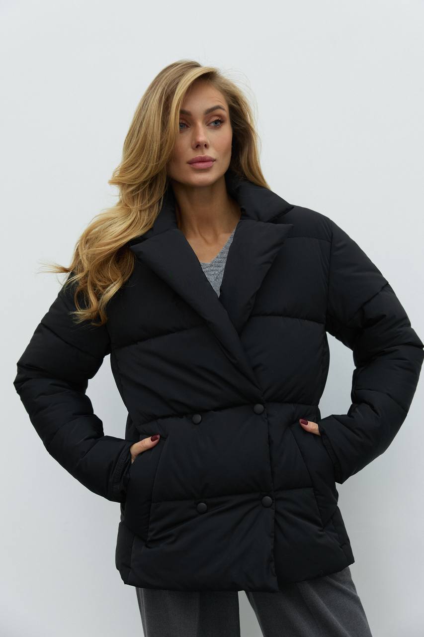 Woman wearing a black puffer coat against a white background