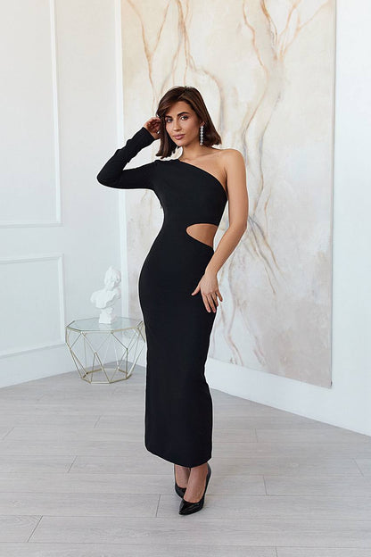 Woman wearing a black one-shoulder dress with cut-out design in a room with marble wall.