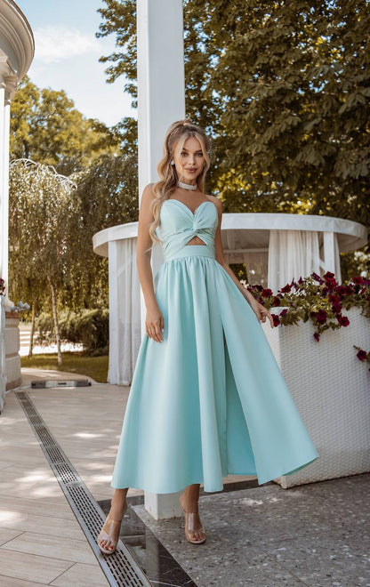 Woman in a light blue dress standing outdoors with trees and a gazebo in the background