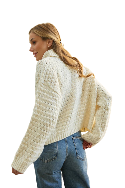 Woman wearing a cream knitted cardigan and blue jeans on a white background